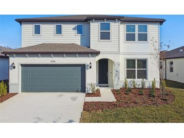 Two-story house with a two-car garage and landscaped front yard at 1244 Kazaz Ct, Zephyrhills, FL 33540