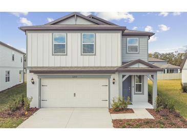 Two-story house with gray and white siding, a two-car garage, and a landscaped yard at 1209 Kistna Dr, Zephyrhills, FL 33540