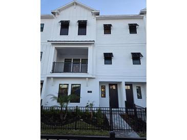 Three-story townhome with modern facade, dark gray door, and small front yard at 7412 Newham Ln, Sarasota, FL 34240
