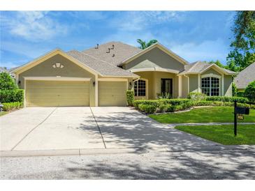 Tan three-car garage house with manicured lawn at 806 Red Ash Ct, Seffner, FL 33584