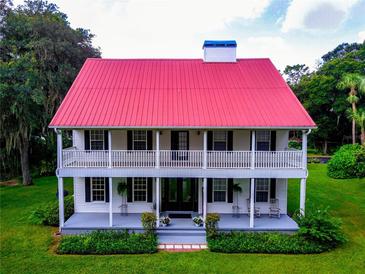 Two-story house with red metal roof, wrap-around porch, and landscaped lawn at 4502 Hill Dr, Valrico, FL 33596