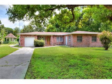 Brick house with driveway, grassy yard, and mature trees at 731 E Lumsden Rd, Brandon, FL 33511