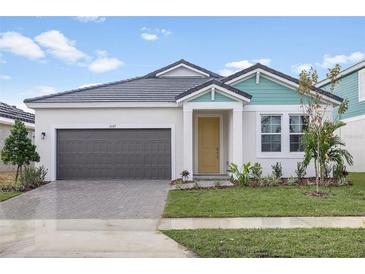 Exterior of charming one-story house with gray garage door and teal accents at 10317 Fieldstone Myrtle Way, San Antonio, FL 33576