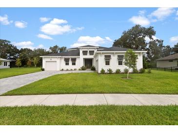 Two-story home with a white exterior, attached garage, and manicured lawn at 15603 Serengeti Blvd, Spring Hill, FL 34610