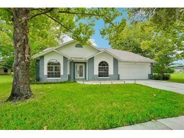 One-story home with gray and white exterior, lush lawn, and two-car garage at 6302 Silver Oaks Dr, Zephyrhills, FL 33542