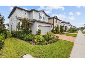 Two-story house with gray siding, landscaping, and a brick driveway at 4578 Emprise Way, Land O Lakes, FL 34638