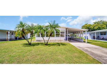 Single-wide manufactured home with carport and palm trees in front at 15 Hamilton Ln # 7, Palm Harbor, FL 34684