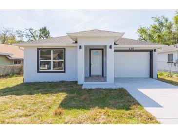 Charming home featuring a white exterior, well-manicured lawn, and an attached single car garage at 2911 E 20Th Ave, Tampa, FL 33605