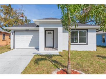 Charming single-story home featuring a well-maintained lawn and a pristine white garage door at 3910 E Genesee St, Tampa, FL 33610