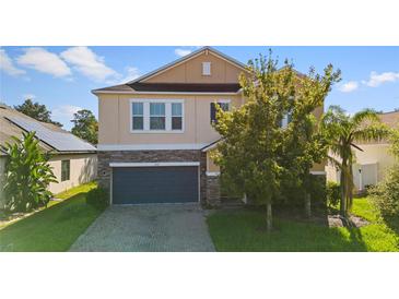 Two-story house with a stone and beige exterior, two-car garage, and landscaping at 3147 Calvano Dr, Land O Lakes, FL 34639