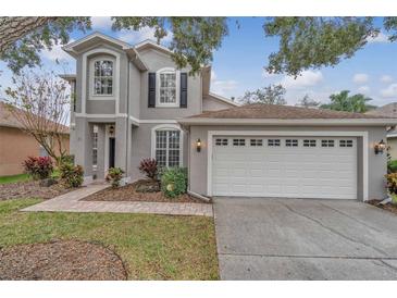 Two-story house with gray siding, white garage door, and landscaping at 10142 Kingsbridge Ave, Tampa, FL 33626