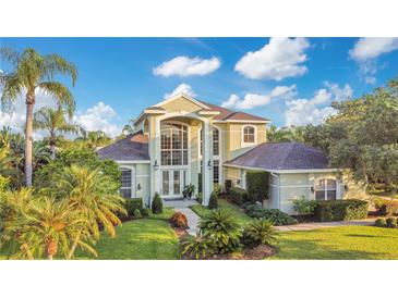 Two-story house with a grand entrance, lush landscaping, and a large yard at 1935 Lago Vista Blvd, Palm Harbor, FL 34685