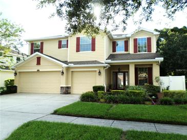 Two-story house with beige siding, red shutters, and a three-car garage at 2387 Bartolo Dr, Land O Lakes, FL 34639