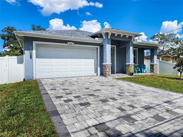 Gray house with white garage door, paver driveway, and landscaped lawn at 2115 W Idlewild Ave, Tampa, FL 33603