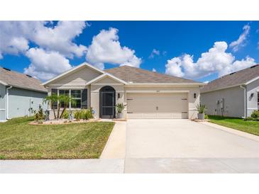 One-story home with beige exterior, landscaping, and two-car garage at 1523 Glen Grove Loop, Wesley Chapel, FL 33543