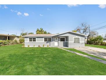 Charming gray home with a well-manicured lawn and front yard landscaping at 541 E Lime St, Tarpon Springs, FL 34689