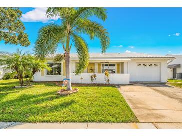 White single-story house with palm trees, driveway, and green lawn at 9125 39Th N Ln, Pinellas Park, FL 33782