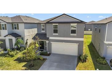 Charming two-story home with a gray exterior, attached garage, and well-maintained front yard at 9917 Spanish Lime Ct, Riverview, FL 33578