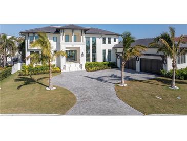 Stunning home showcasing a paver driveway, manicured lawn, tropical landscaping, and an attached three-car garage at 105 Cordova Ne Blvd, St Petersburg, FL 33704