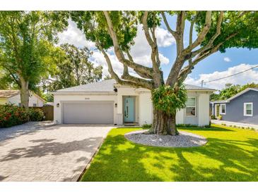 Charming single-story home with a beautiful mature tree in the front yard and a gray two car garage at 3604 W Paxton Ave, Tampa, FL 33611