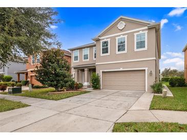 Two-story house with tan exterior, three-car garage, and landscaping at 20213 Autumn Fern Ave, Tampa, FL 33647