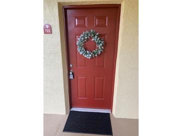 Welcoming red front door featuring a decorative wreath and unit number 722 at 2690 Coral Landings Blvd # 722, Palm Harbor, FL 34684