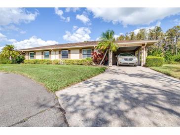 Charming single-story home with a well-manicured lawn, a carport, and beautiful landscaping at 2104 Hembury Pl # 33, Sun City Center, FL 33573