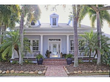 Light blue house with white columns, brick walkway, and lush landscaping at 618 Islebay Dr, Apollo Beach, FL 33572