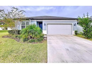 Single-story home with gray exterior, two-car garage, and landscaped lawn at 6119 Bradford Woods Dr, Zephyrhills, FL 33542