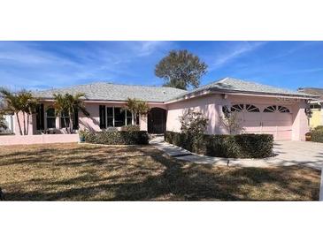 Pink one-story house with a two-car garage and manicured landscaping at 2833 Windridge Dr, Holiday, FL 34691