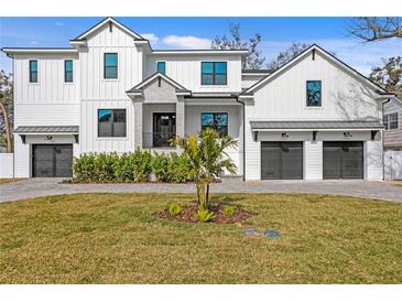 Two-story white farmhouse with gray accents, two-car garage, and manicured lawn at 4835 W San Jose St, Tampa, FL 33629