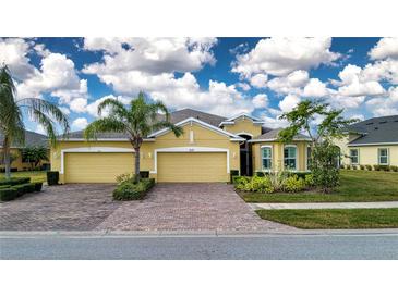 Two-story house with a three-car garage, landscaping, and brick driveway at 649 Chipper Dr, Sun City Center, FL 33573