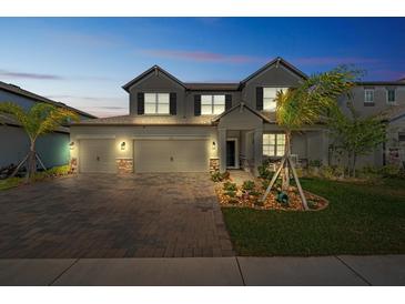 Two-story house with three-car garage, landscaping, and a paved driveway at 3133 King Fern Dr, Wimauma, FL 33598