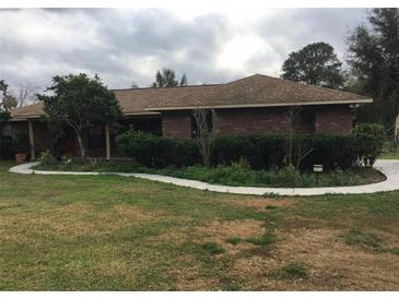 Charming single-story brick home featuring a well-maintained lawn and manicured landscaping at 2815 Kebs Ln, Plant City, FL 33565