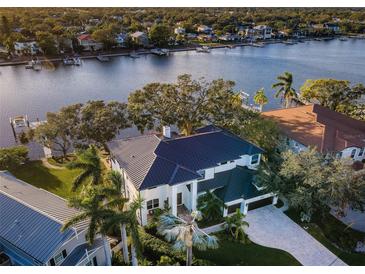 Stunning waterfront home with a metal roof, lush landscaping, and a private boat dock along a serene waterway at 1100 Monterey Ne Blvd, St Petersburg, FL 33704