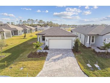 Single-story home with gray roof, white garage door, and landscaped yard at 9461 Shorebird Ct, Parrish, FL 34219