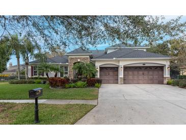 Two-story home with stone accents, three-car garage, and landscaped yard at 16623 Ashton Green Dr, Lutz, FL 33558