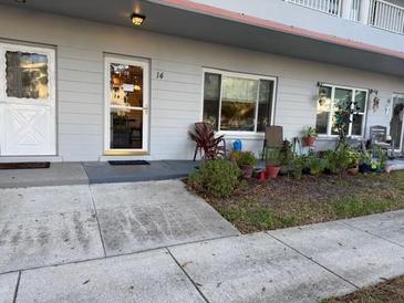 Exterior view of condo building, showing unit entrance with landscaping and walkway at 2100 World Parkway Blvd # 14, Clearwater, FL 33763