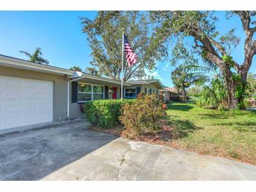 Charming single-story home featuring mature landscaping, a patriotic flag, and a welcoming red front door at 164 23Rd Sw Ave, Largo, FL 33778