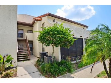 Charming two-story condo featuring a staircase, landscaping, and a stucco exterior, creating an inviting curb appeal at 2595 Cyprus Dr # 4-202, Palm Harbor, FL 34684