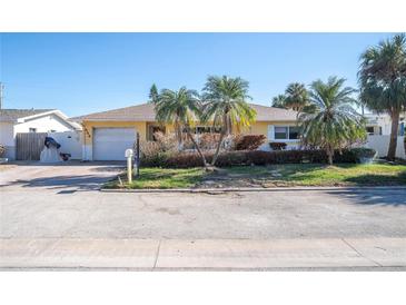 Single-story home with a yellow exterior, attached garage, and palm trees at 444 90Th Ave, St Pete Beach, FL 33706