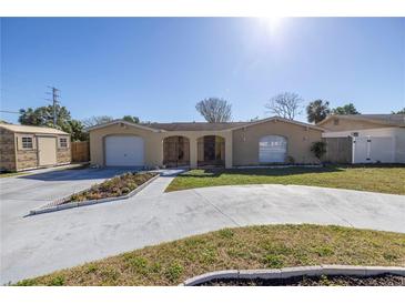 Charming home featuring a well-manicured lawn, extended driveway, and an inviting, gated front patio at 7430 Buchanan Dr, Port Richey, FL 34668