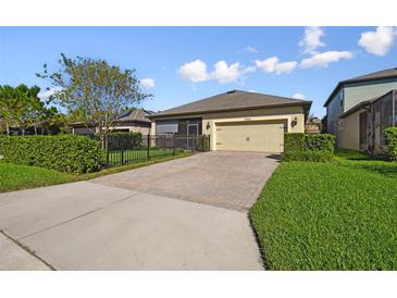 Tan house with a two-car garage and landscaped yard at 12926 Payton St, Odessa, FL 33556