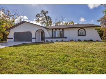 Modern home with a dark gray garage and white exterior at 4290 Yucatan Cir, Port Charlotte, FL 33948
