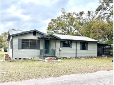 Charming single-story home featuring light green siding, dark trim and shutters, and a metal roof at 18802 3Rd Se St, Lutz, FL 33549