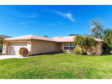 Tan one-story house with attached garage, well-maintained lawn, and tropical landscaping at 3276 Buckhorn Dr, Clearwater, FL 33761