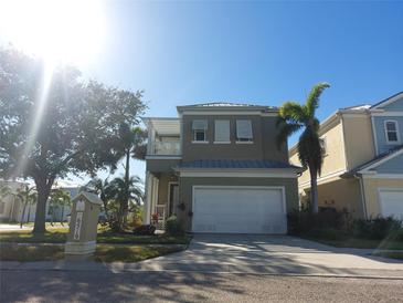 Two-story house with a gray facade, white garage door, and palm trees at 6519 Simone Shores Cir, Apollo Beach, FL 33572