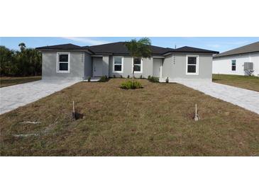 New gray house with gray pavers driveway, landscaping and palm tree at 10402 Pendleton Ave, Englewood, FL 34224