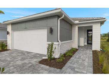 Modern home exterior with gray siding, white garage door, and a paved walkway at 11170 Livewell Ct, Venice, FL 34293