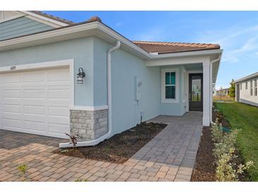 Exterior view of a light blue house with a walkway, garage, and landscaping at 11275 Boundless Ter, Venice, FL 34293